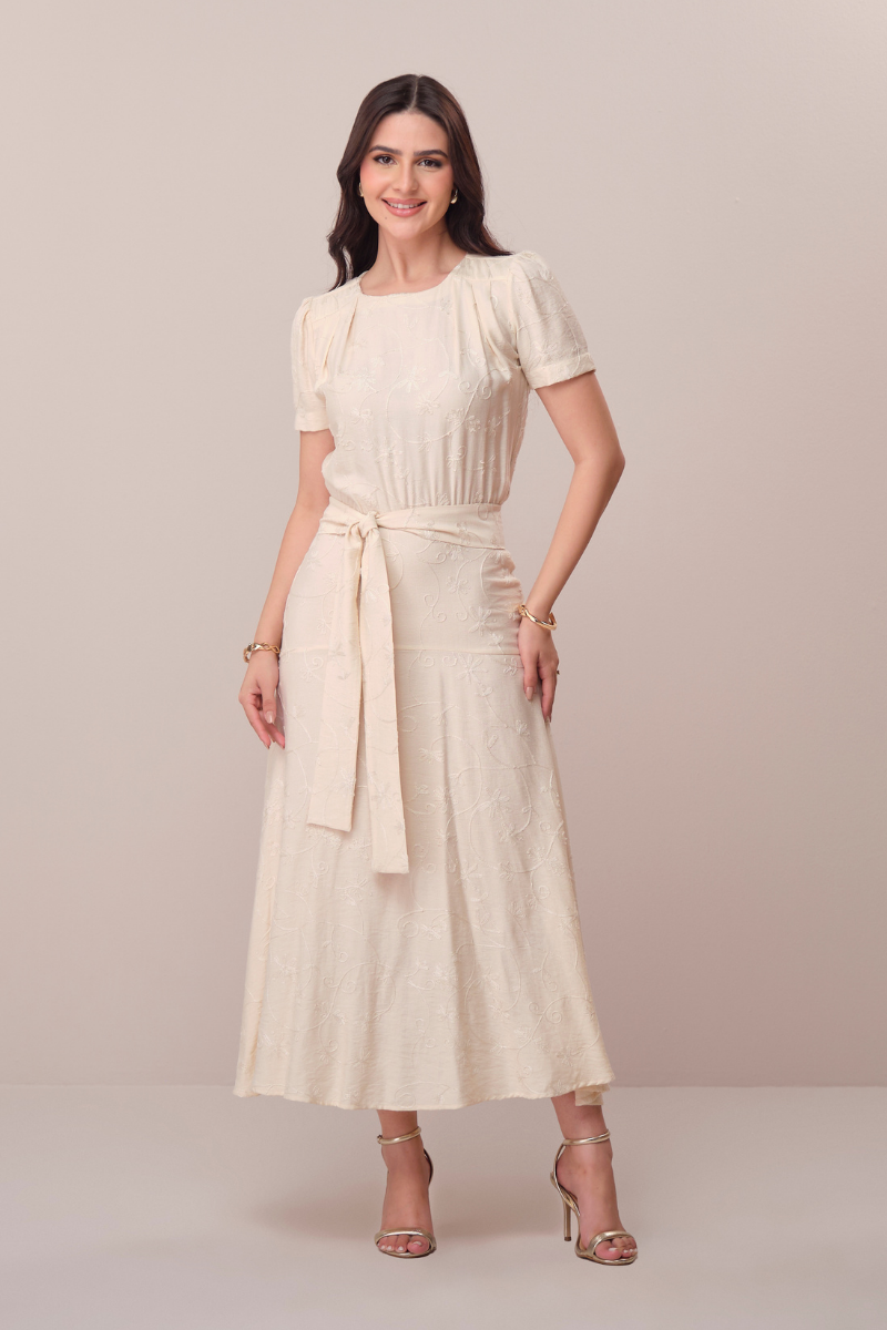 Modelo vestindo um elegante vestido midi bege de alta costura em um ambiente minimalista e luxuoso.