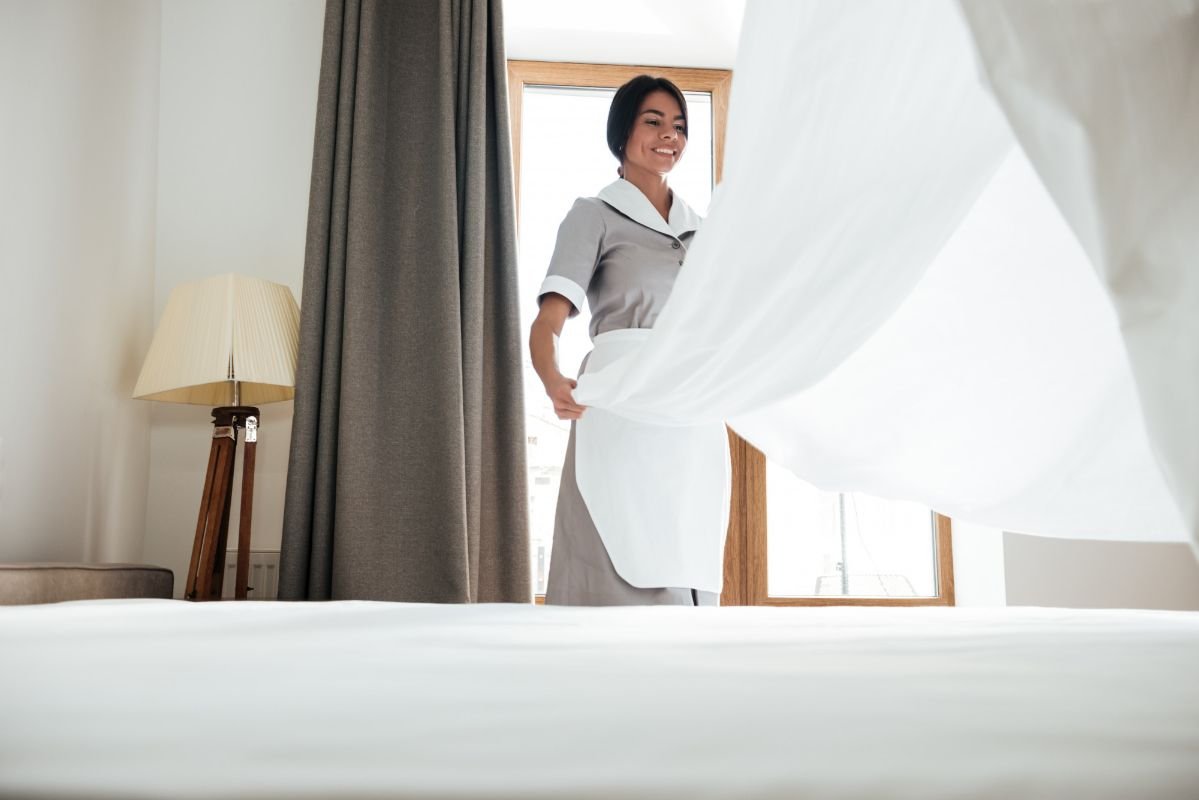 camareira arrumando cama de hotel