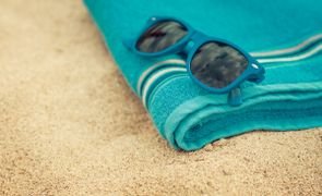óculos de sol em cima de toalha de praia