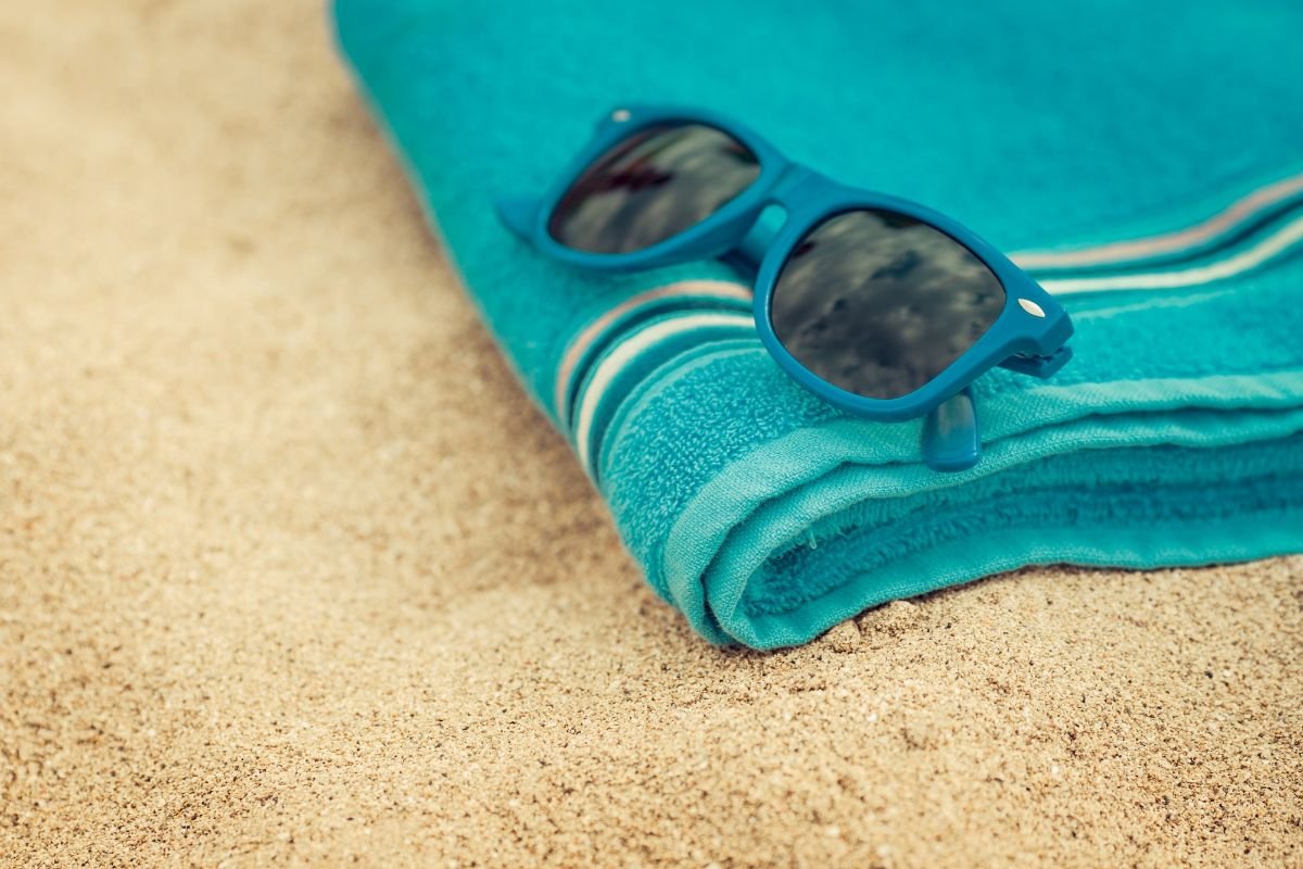 óculos de sol em cima de toalha de praia
