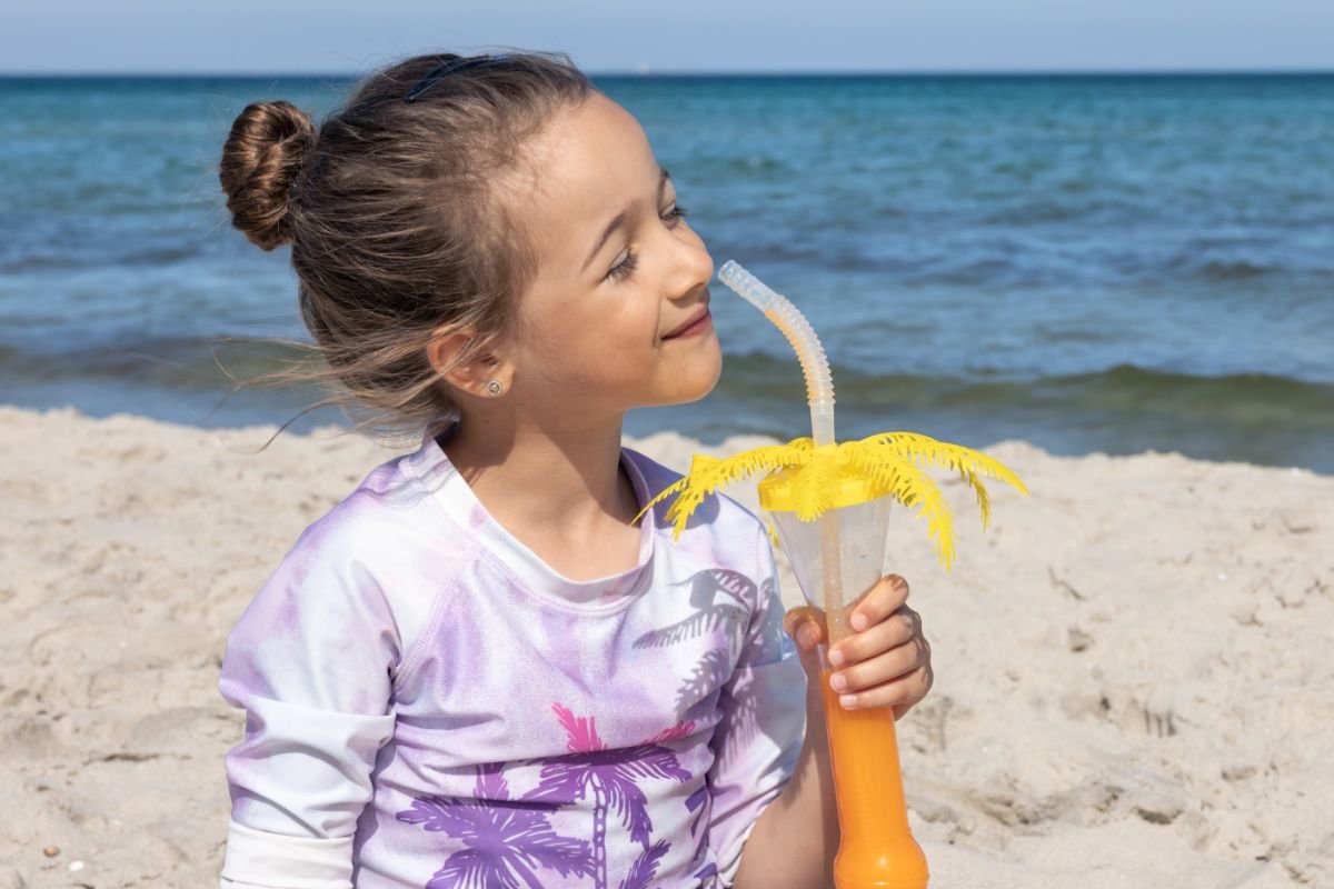 menina tomando suco na praia