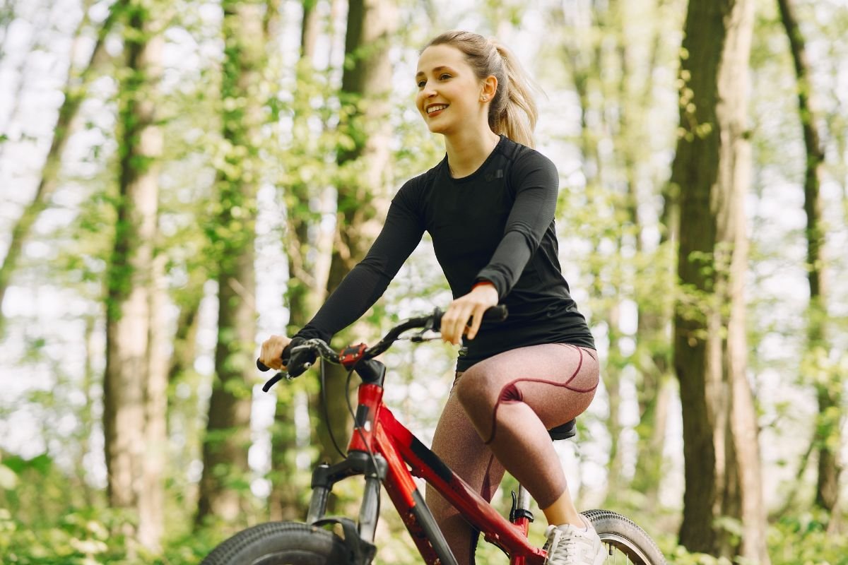 garota loira andando de bicicleta no bosque