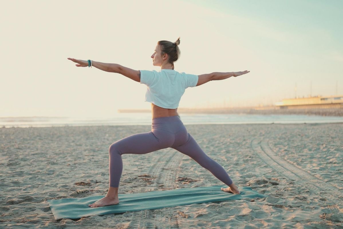 mulher praticando yoga na praia