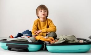 menino organizando mala com roupa infantil para viajem