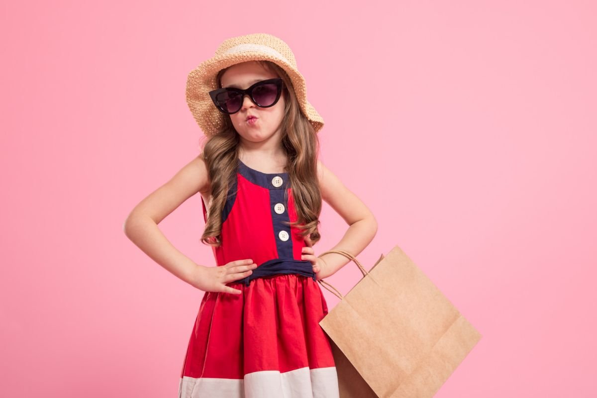 menina com vestido vermelho segurando sacola de compras