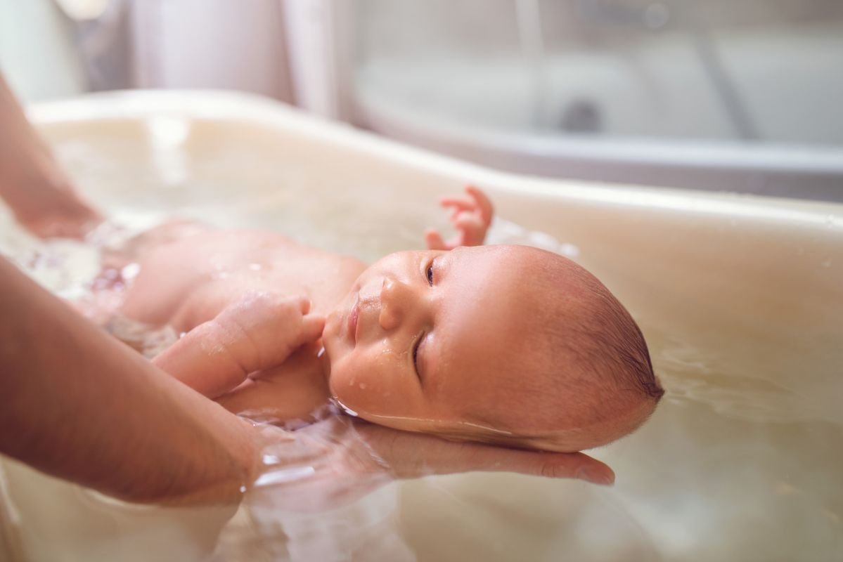 dando banho em banheira tomando os cuidados com a moleira do bebê