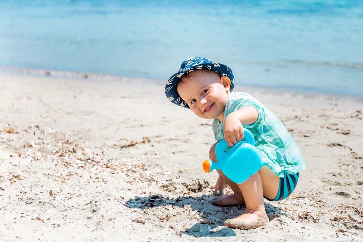 menino brincando na areia da praia