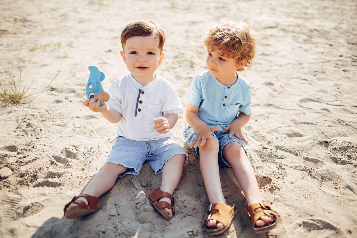 meninos sentados na areia da praia