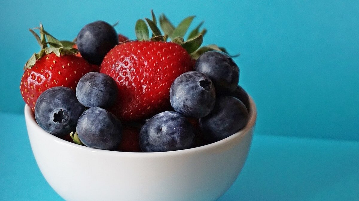 Frutas em um pote branco com fundo azul