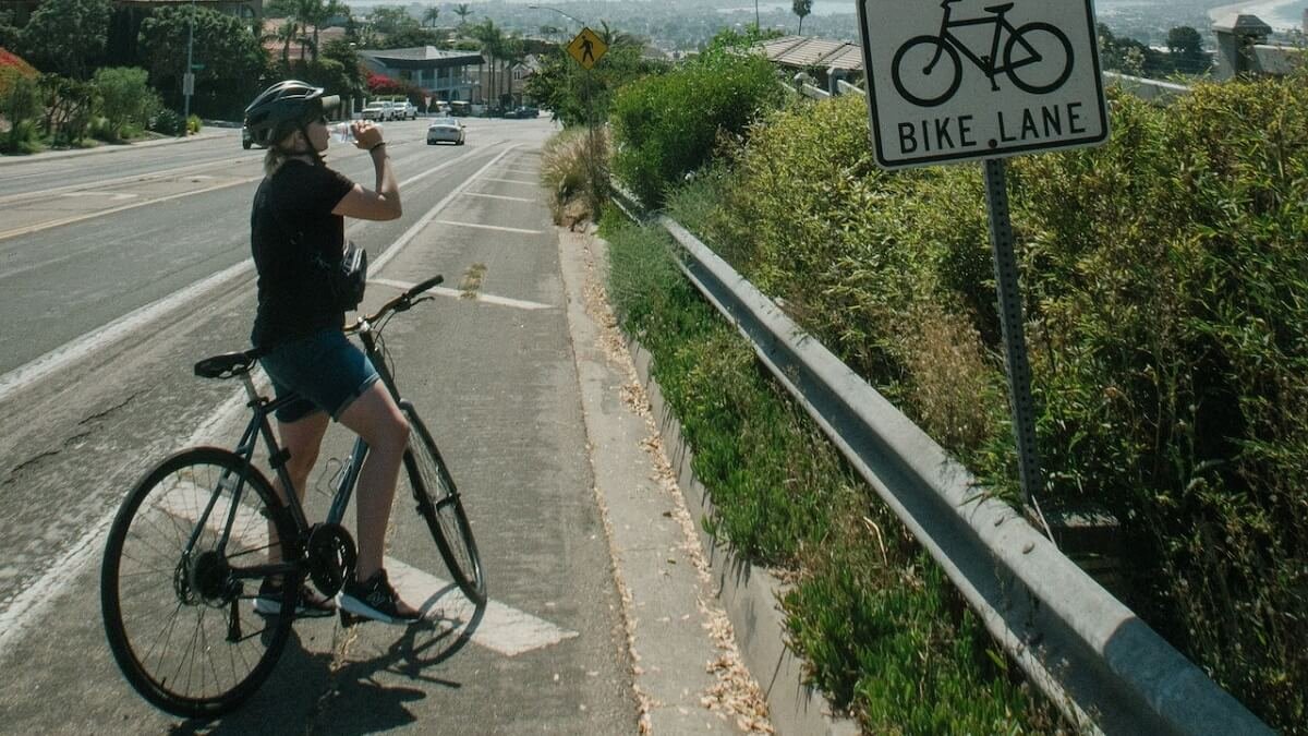 Ciclista bebendo água em beira de rodovia