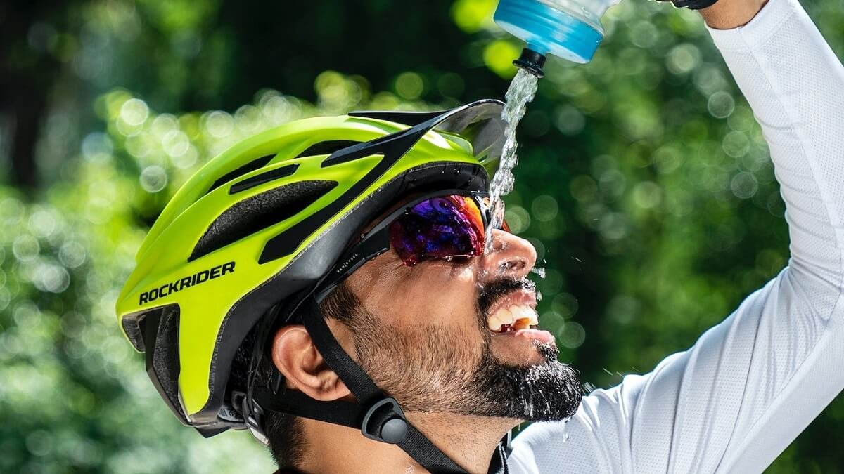 Ciclista jogando água em seu rosto em um dia ensolarado