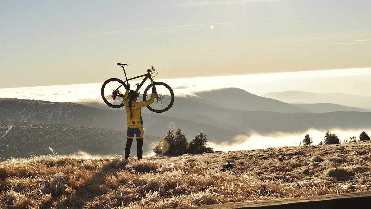 Pessoa segurando a bicicleta no alto de uma montanha