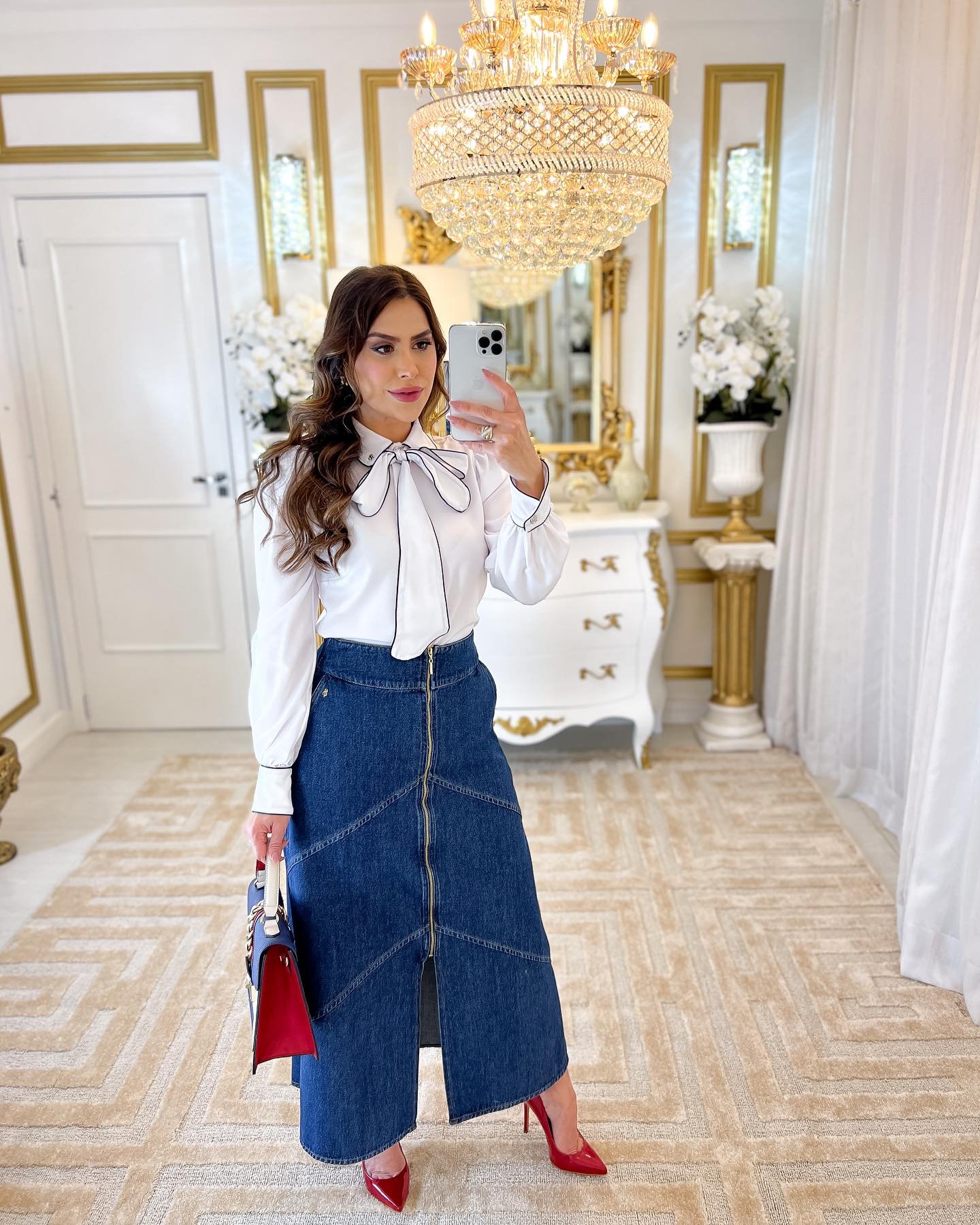 influenciadora Angela Mendes com saia evasê jeans com zíper e fenda central combinada com camisa branca com laço no pescoço